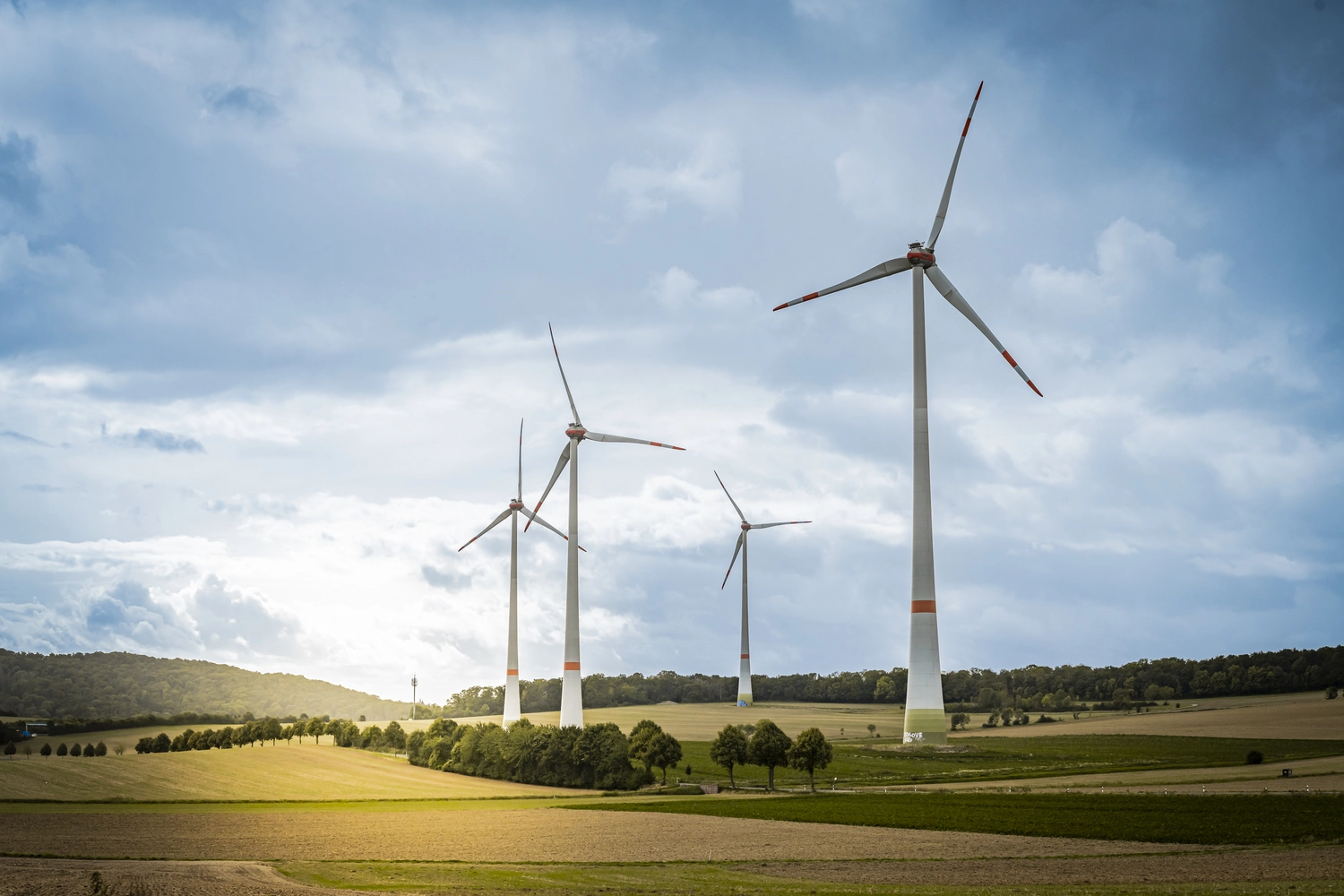 Lohrengel Consulting – Erneuerbare Energien – ein Windpark, der aus mehreren großen Windkraftanlagen auf einem Feld unter blauem Himmel besteht